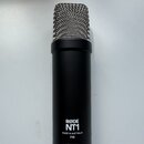 Černý kondenzátorový mikrofon s kovovou stříbrnou mřížkou. Na spodní části těla je bílý nápis RØDE NT1 a pod ním text MADE IN AUSTRALIA P48. Povrch m…
