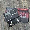 Černý kytarový efekt s nápisem M5 STOMPBOX MODELER a logem LINE 6. Zařízení má displej, čtyři ovládací knofíky a dva spínací pedály s nápisy ON / OFF…