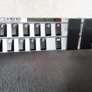 Šedý MIDI kontrolér s nápisem FCB1010 MIDI FOOT CONTROLLER. Zařízení obsahuje dvě řady černých spínacích pedálů s bílými čísly 1 až 10 a tlačítky UP…