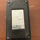 Zadní strana černého efektového pedálu s bílým štítkem. Na štítku je nápis ADAPTOR JACK DC9VOLT, instrukce v japonštině a angličtině, text SERIAL No…