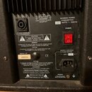 Fotografie zachycuje zadní panel černého elektronického zařízení s chladičovými žebry v horní části. Je zde vidět výstup EXT. SPEAKER s nápisem 8 OHM…