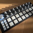 Černý MIDI kontrolér s bílými podsvícenými pady a šedimi otočnými knoflíky. Na levé straně je bílý nápis ARTURIA a pod ním text YOUR EXPERIENCE YOUR…