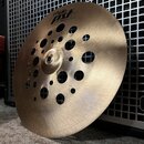 Zlatý kovový činely s perforací v podobě zahlreichen kulatých otvorů různých velikostí. Na povrchu je černý nápis paiste PST X a pod ním menší text 1…
