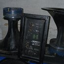 Černý reproduktorový systém s modrými prvky. Na zadním panelu je viditelný nápis RENKUD210RKX, model PF1-500R a logo RHA. Panel obsahuje několik kone…