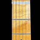 Fotografie zachycuje hmatník a hlavu elektrické kytary z jasně žlutého dřeva. Na hlavě je vidět kurzivní logo Fender a vedle něj nápis "TELECASTER".…