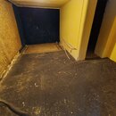 Fotografie nezobrazuje žádný hudební nástroj ani příslušenství. Je na ní vidět prázdná místnost s tmavou podlahou a žlutými stěnami. V pozadí je vidě…