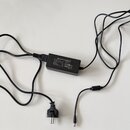 Černý síťový adaptér s dvěma kabely a koncovkou typu DC. Na štítku je nápis SWITCHING ADAPTER, MODEL: AC-120500 a ATTENTION. Jsou zde rovněž viditeln…