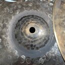Fotografie zachycuje detail dvou kovových činelů s kovaným povrchem a viditelnými kladivovými rýhami. Činely mají tmavší, patinovaný mosazný odstín a…