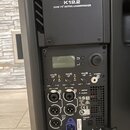Zadní panel černého aktivního reproduktoru s nápisem QSC K12.2 2KW 75° ACTIVE LOUDSPEAKER. Panel obsahuje LCD displej, tři ovratové knoflíky GAIN (A,…