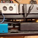 Zadávací panel stříbrného zařízení s nápisy OUTPUT STEREO, DC IN 9V 600mA a MIDI (včetně konektorů IN a THRU). Vedle něj je umístěno další stříbrné z…