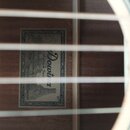 Fotografie zachycuje vnitřek akustického nástroje s viditelnými žebry a štítkem nalepeným na desce. Na štítku je nápis „Downbeat Antique Series Rusti…