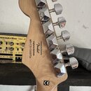 Zadní strana hlavy kytary z přírodního dřeva s chromovanými ladičkami. Na dřevě je černý nápis „Designed and Backed by Fender“, „Crafted in Indonesia…