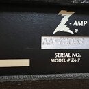 Detail zadní strany černého přístroje s texturou. Je zde bílé logo Z-AMP a pod ním stříbrná ploška s číslem AA 72058. Dole je uveden nápis SERIAL NO.…