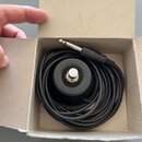 V kartonové krabici je srolovaný černý kabel zakončený 6,3mm jack konektorem. Uprostřed kabelu se nachází černý cylindrický komponent s kovovým stisk…