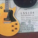 Žlutá elektrická kytara typu Les Paul s černým pickguardem a čtyřmi ovládacími knoflíky. Vedle nástroje je umístěn informační štítek s nápisy STB, LS…