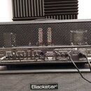 Zadní strana kytarového komba s černým povrchem a kovovou mřížkou. Na zadním panelu jsou viditelné nápisy USB AUDIO, FOOTSWITCH, EFFECTS LOOP, REVERB…