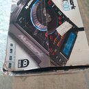 Fotografie znázorňuje poškozenou kartonovou krabici s obrázkem DJ playeru. Na krabici jsou viditelná loga Numark, Serato a nápisy NDX500, VERSATILE D…