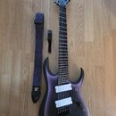 Elektrická kytara s fialovým přechodovým lakem a černým matem, doplněná o vzorovaný modrý popruh s nápisem "Steve Vai". Na hlavě hmatníku je bílé log…