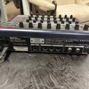 Zadní strana modrého MIDI kontroléru s názvy BEHRINGER MODEL BCR2000 a B-CONTROL ROTARY BCR2000. Jsou zde viditelné konektory USB, MIDI (OUT B/THRU,…
