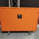 Zadní strana oranžové kytarové reprobedny na čtyřech kolečkách. Uprostřed je černý štítek s bílým nápisem: Orange, CE, 1200 W RMS, 8 OHMS, Load Speak…
