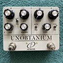 Bílý kytarový efekt s nápisem UNOBTANIUM a logem crazy tube circuits. Zařízení má osm ovládacích knobů s popisky volume, gain, volume, gain, tone, em…