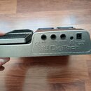 Zadní strana šedého efektového pedálu s výrazným nápisem Digitech. Jsou zde vidět čtyři konektory s popisky INPUT, LEFT OUT, RIGHT OUT a 9VDC 300mA s…