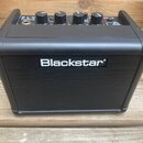 Černý kompaktní kytarový zesilovač s nápisem Blackstar na přední mřížce. Na horní ovládací ploše jsou čtyři otočné knoflíky a nápisy FLY, 3 WATT MINI…