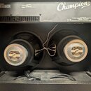 Fotografie zachycuje vnitřek kytarového komba se dvěma reproduktory. Na horní části je bílý nápis MODEL Champion 100 a logo Fender s textem A PRODUCT…