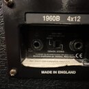 Detail zadní strany kytarového boxu s černým povrchem. Na horním štítku je nápis 1960B 4x12. Pod ním se nachází ovládací panel s dvěma vstupy a přepí…