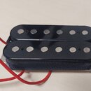 Černý humbucker s dvěma řadami šesti kovových pólů. Snímač je obalen černou tkanou páskou a má připojený červený kabel. Na komponentu nejsou viditeln…