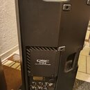 Zadní strana černého aktivního reproduktoru. Na zadním panelu je viditelné logo QSC a nápis K12.2 2 KW 75" ACTIVE LOUDSPEAKER. Dole se nachází ovláda…