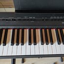 Černý digitální klavír s bílými a černými klávesami. Na ovládacím panelu je vpravo bílé logo YAMAHA a řada tlačítek s nápisy jako MASTER VOLUME, DEMO…
