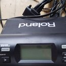 Černý elektronický modul s nápisem Roland TD-4 PERCUSSION SOUND MODULE. Na přední straně jsou tlačítka POWER, TUNING, MUFFLING, DRUM KIT, MENU, SEL,…
