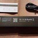 Fotografie zobrazuje černou obdélníkovou krabici, černý USB kabel a bílý papírový manuál. Na spodní straně krabice je nápis CHOCOLATE PLUS Wireless M…