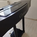Černý digitální piano v doprovodu stojanu. Na boku korpusu je bílý nápis Clavinova, který se opakuje i v odrazu na horní deskách. Povrch je hladký a…