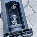 Černý kovový svíticí reflektor s otevřeným vnitřkem. Uvnitř je vidět žárovka v patronom s připojeným elektrickým kabelem. Zařízení vykazuje známky po…