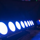 Fotografie zobrazuje dvě svítící LED lampy v modrém světle. V popředí je dlouhá lineární lampa s osmi kulatými bílými světelnými zdroji. V pozadí je…