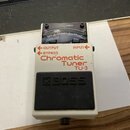 Bílý kytarový ladič značky BOSS, model TU-3 Chromatic Tuner. Na horní straně je umístěn displej s analogovou stupnicou a nápisem CHECK. V dolní části…