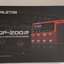 Fotografie znázorňuje krabici od efektového procesoru. Na černé krabici je bílý nápis VALETON a modelové označení GP-200R MULTI-EFFECTS PROCESSOR. V…