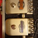 Dvě zlatavé efektové pedály značky Marshall v přepravním kufru. Horní pedal má nápis REFLECTOR REVERB a označení RE-1, spodní pedal má nápis ECHOHEAD…