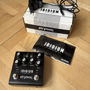 Černý kytarový pedál s nápisy IRIDIUM, amp & ir cab a strymon. Zařízení má několik ovládacích knoflíků s popisky DRIVE, MIDDLE, TREBLE a LEVEL, dva s…