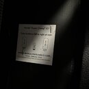 Fotografie zachycuje bílý papírový štítek nalepený na černém povrchu. Štítek obsahuje text Model "Super Champ® X2" a nápis Tube locations left to rig…