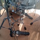 Detailní pohled na chromované části bicí sady a pedály. Na koruse bubnu je vidět kulatý štitek s nápisem „SONOR“. V popředí jsou dva chromované pedál…