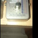 Stříbrný efekt pedál s nápisem INTELLIGENT HARMONY MACHINE a logem electro-harmonix NEW YORK CITY, USA. Na horní straně jsou tři černé otočné ovladač…