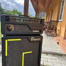 Černý kytarový zesilovač a reproduktor umístěné na sobě. Horní jednotka má nápisy Tech 21 NYC New York City Brilliance Co. a Neural, s ovládacími prv…