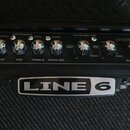 Kytarový kombo zesilovač značky LINE 6, model SPIDER IV 15. Horní ovládací panel obsahuje osm otočných knoflíků s nápisy DRIVE, BASS, MID, TREBLE, CH…