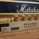 Detailní pohled na přední panel zlatého kytarového zesilovače. Na horní části je bílé logo Marshall a níže nápis 9100 Dual MonoBloc System. Na panelu…