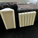 Dvě bílé akustické pěnové panely s drážkovaným povrchem. Panely mají tvar obdélníku a jsou umístěny vedle sebe na tmavém povrchu. Na fotografiích nej…