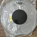 Průhledná bubenová kožíška v originálním plastovém obalu. Uprostřed je černý tlumicí kruh a v horní části nápisy REMO, CONTROLLED SOUND CLEAR a Made…