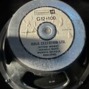 Fotografie zachycuje zadní stranu reproduktoru. Na bílé štítku je uveden název Celestion, model G12-100 a impedance 8 ohms. Štítek nese nápis ROLA CE…